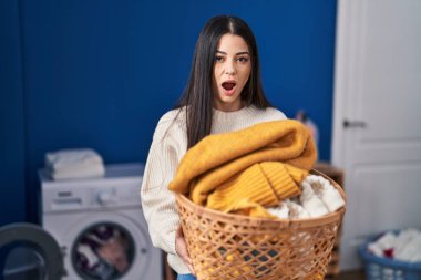 Çamaşır sepetini tutan genç bir kadın şaşkınlık ve şaşkınlık dolu bir ifade, korku ve heyecanlı bir yüz ifadesiyle şok olmuştu.. 