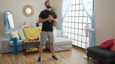 Dambıl kullanan genç bir İspanyol evde bacak egzersizi yapıyor.