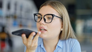 Genç sarışın iş kadını ofiste çalışan akıllı telefondan sesli mesaj gönderiyor.