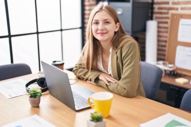 Ofiste çalışan genç beyaz kadın iş adamı dizüstü bilgisayar kullanıyor.
