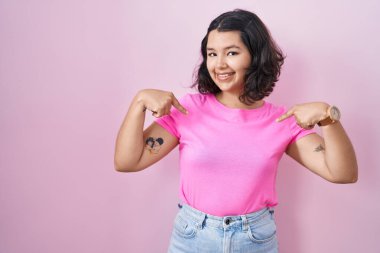 Pembe arka planda duran, kendine güvenen, kendini gururlu ve mutlu gösteren genç İspanyol kadın.. 