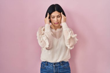 Pembe arka planda duran Asyalı genç bir kadın. Stres yüzünden baş ağrısı çekiyor. migren ağrısı. 