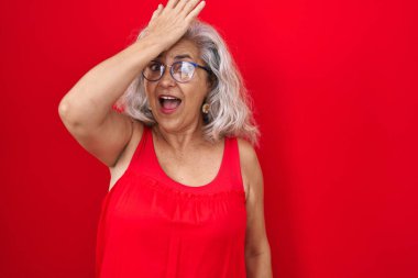 Kırmızı arka planda gri saçlı, orta yaşlı bir kadın. Hatayla el ele tutuşup şaşırdı. Hatayı hatırla. Unuttum, kötü hafıza kavramı. 