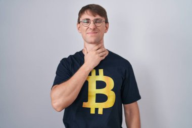 Beyaz, sarışın, bitcoin tişört giyen, boynu ağrıyan, boğazı ağrıyan, grip, mantar ve enfeksiyon kapmış bir adam. 