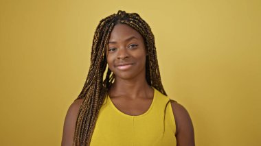 Sarı arka planda duran kendine güvenen Afrikalı Amerikalı kadın.