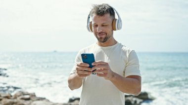 Kumsalda akıllı telefon kullanan genç bir adam.