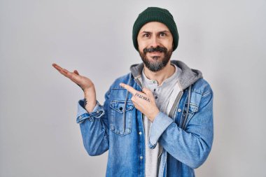 Yün şapka takan İspanyol asıllı genç adam kameraya hayret ediyor ve gülümsüyor.. 