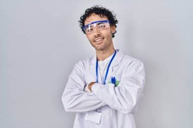 Laboratuvarda çalışan İspanyol bir adam kameraya bakarken kollarını kavuşturup gülümsüyor. pozitif kişi. 