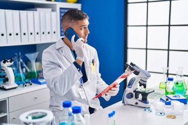 Genç İspanyol bilim adamı laboratuvardaki akıllı telefon okuma belgesiyle konuşuyor.