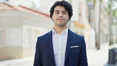 Sokakta rahat bir ifadeyle duran genç Latin iş adamı.