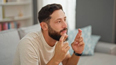 Kanepede oturan genç İspanyol adam şans diliyor.