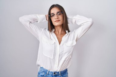 Genç esmer kadın gözlük takıyor, rahatlıyor ve esniyor, kolları ve elleri başının arkasında mutlu bir şekilde gülümsüyor. 