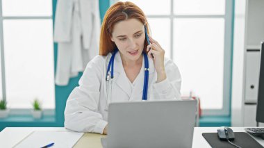 Genç kızıl saçlı kadın. Klinikte bilgisayarla konuşuyor.