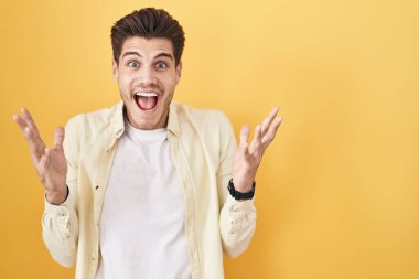 Sarı arka planda duran genç İspanyol adam çılgın ve başarıyı kollarını kaldırıp heyecanla haykırarak kutluyor. Kazanan konsept 