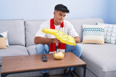 Evdeki kanepede oturan İspanyol futbolu takımını destekleyen genç adam.