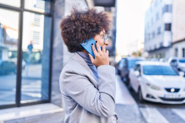 Afro-Amerikan kadın yönetici gülümsüyor. Akıllı telefondan konuşuyor.