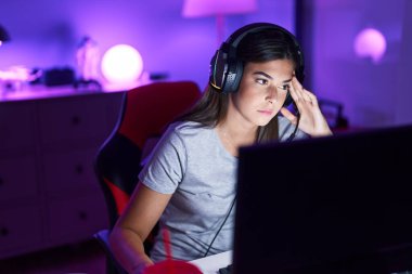 Young beautiful hispanic woman streamer playing video game using computer at gaming room