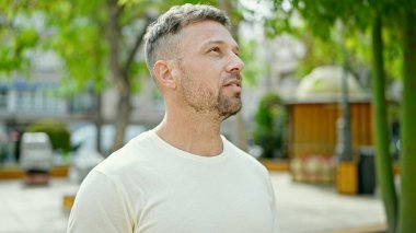 Parkta ciddi bir yüzle gökyüzüne bakan genç adam.