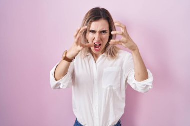 Pembe arka planda duran genç ve güzel bir kadın öfkeyle bağırıyor, elleri boğmaya çalışıyor, deli gibi bağırıyor. 