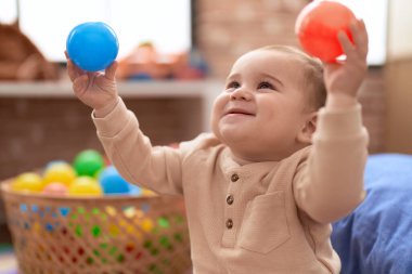 Anaokulunda yerde oturmuş hayalarıyla oynayan sevimli çocuk.