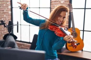 Genç bayan müzisyen müzik stüdyosunda keman çalıyor.