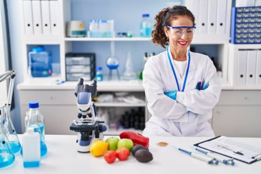 Orta yaşlı İspanyol kadın laboratuvarda çapraz kollarla çalışıyor.