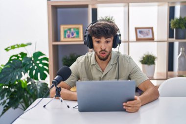 Radyoda çalışan sakallı bir Arap. Korkmuş ve ağzı açık kalmış, şaşırmış, inançsız bir yüz. 