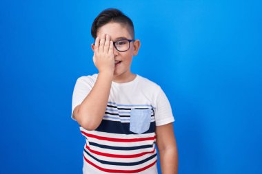 Mavi arka planda duran genç İspanyol çocuk bir gözünü eliyle kapatıyor, yüzünde kendine güvenen bir gülümseme ve sürpriz bir duygu var.. 