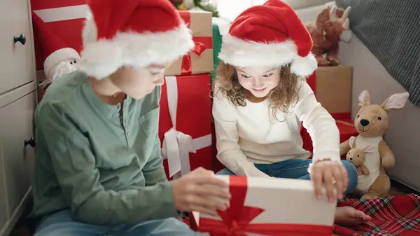 Двое Детей Распаковывают Подарок Сидя Дома Полу Новогодней Елки — стоковое фото
