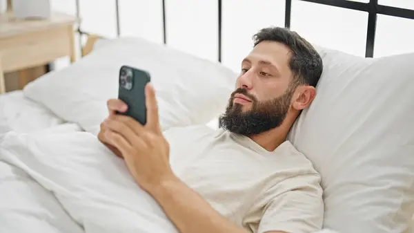 Young Hispanic Man Using Smartphone Sitting Bed Bedroom — 图库照片