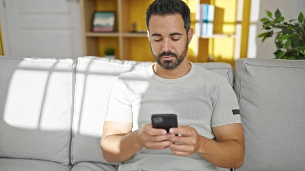 Mladý Hispánec Používá Smartphone Vážným Výrazem Doma — Stock fotografie