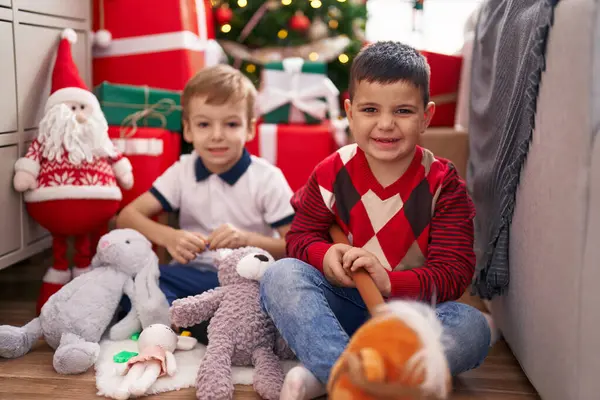 Двое Малышей Играют Игрушками Сидя Дома Полу Новогодней Елки — стоковое фото