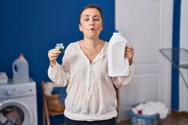 Middle Age Hispanic Woman Holding Detergent Bottle Making Fish Face — Stock Photo, Image