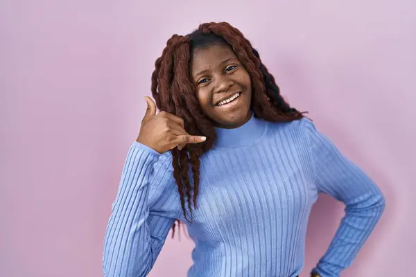 Pembe Arka Planda Durup Gülümseyen Afrikalı Kadın Telefonla Parmaklarıyla Jest — Stok fotoğraf