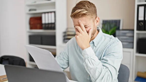 年轻的高加索男性商人在办公室使用笔记本电脑阅读文档时感到压力 — 图库照片