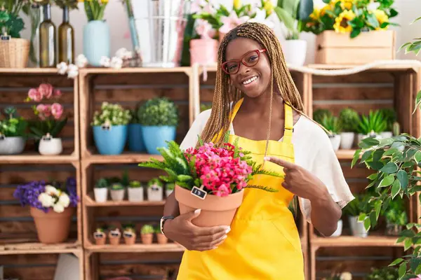 Mujer Afroamericana Con Cabello Trenzado Trabajando Floristería Sosteniendo Planta Sonriendo — Foto de Stock
