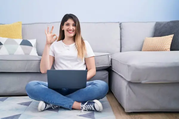Genç Esmer Kadın Dizüstü Bilgisayarını Kullanarak Yerde Oturuyor Parmaklarıyla Işaret — Stok fotoğraf