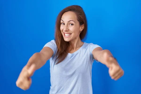 布鲁内特女人站在蓝色的背景上 赞成用手做一个积极的手势 微笑着竖起大拇指 为成功感到高兴 优胜手势 — 图库照片