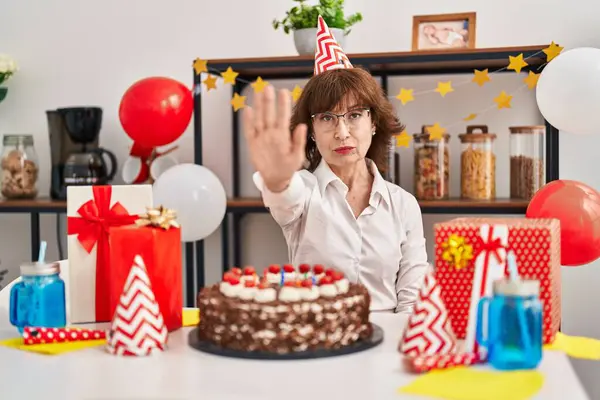 中年妇女举着大大的巧克力蛋糕庆祝生日 张开手 严肃而自信地做着停止手势 做着防守动作 — 图库照片