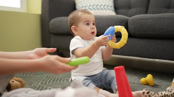 Adorable toddler playing with plastic hoops sitting on floor at home