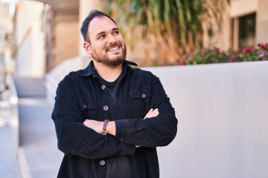 Young hispanic man smiling confident standing with arms crossed gesture at street