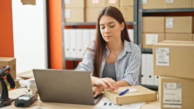 Genç, İspanyol bir kadın, iş kadını. Ofiste dizüstü bilgisayar kullanıyor.