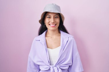 Pembe arka planda duran, yüzünde mutlu ve havalı bir gülümseme olan şapkalı İspanyol bir kadın. şanslı kişi. 