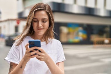 Sokakta akıllı telefon kullanan kendine güvenen genç bir kadın.