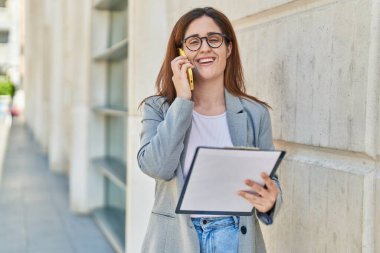 Sokakta akıllı telefon okuyarak konuşan genç iş kadını.