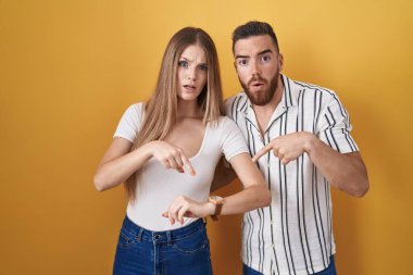 Sarı arka planda dikilen genç çift saati, sabırsızlığı ve gecikmeyi işaret ediyor. 