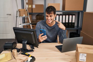 Küçük işletme şirketinde çalışan genç İspanyol bir adam akıllı telefon kullanıyor. Korkmuş ve ağzı açık bir şekilde şaşırmış, inançsız bir yüz kullanıyor. 