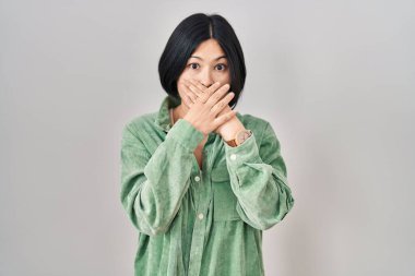 Beyaz arka planda duran Asyalı genç bir kadın yanlışlıkla elleri ile ağzını kapatırken şok oldu. gizli kavram. 