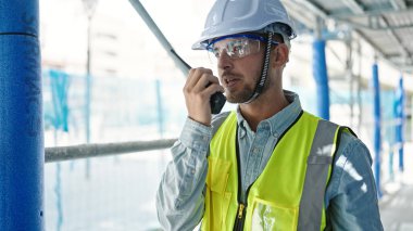 Kafkasyalı genç mimar inşaat alanında telsizle konuşuyor.