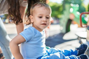 Anne ve oğlu parkta salıncakta sallanıyor.